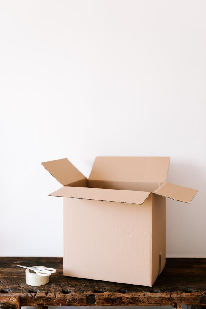 Carton box and tape with scissors on shabby table